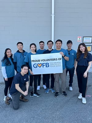 Group of people posing with a banner that reads: 'PROUD VOLUNTEERS OF GVFB THE GREATER VANCOUVER FOOD BANK.'