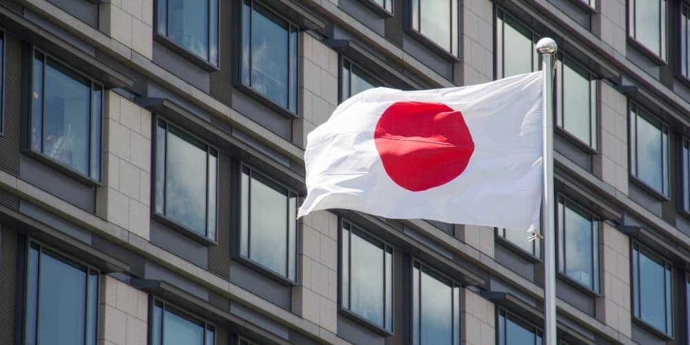Japanese flag waving in the wind against backdrop of modern building Japanese flag waving in the wind against backdrop of modern building