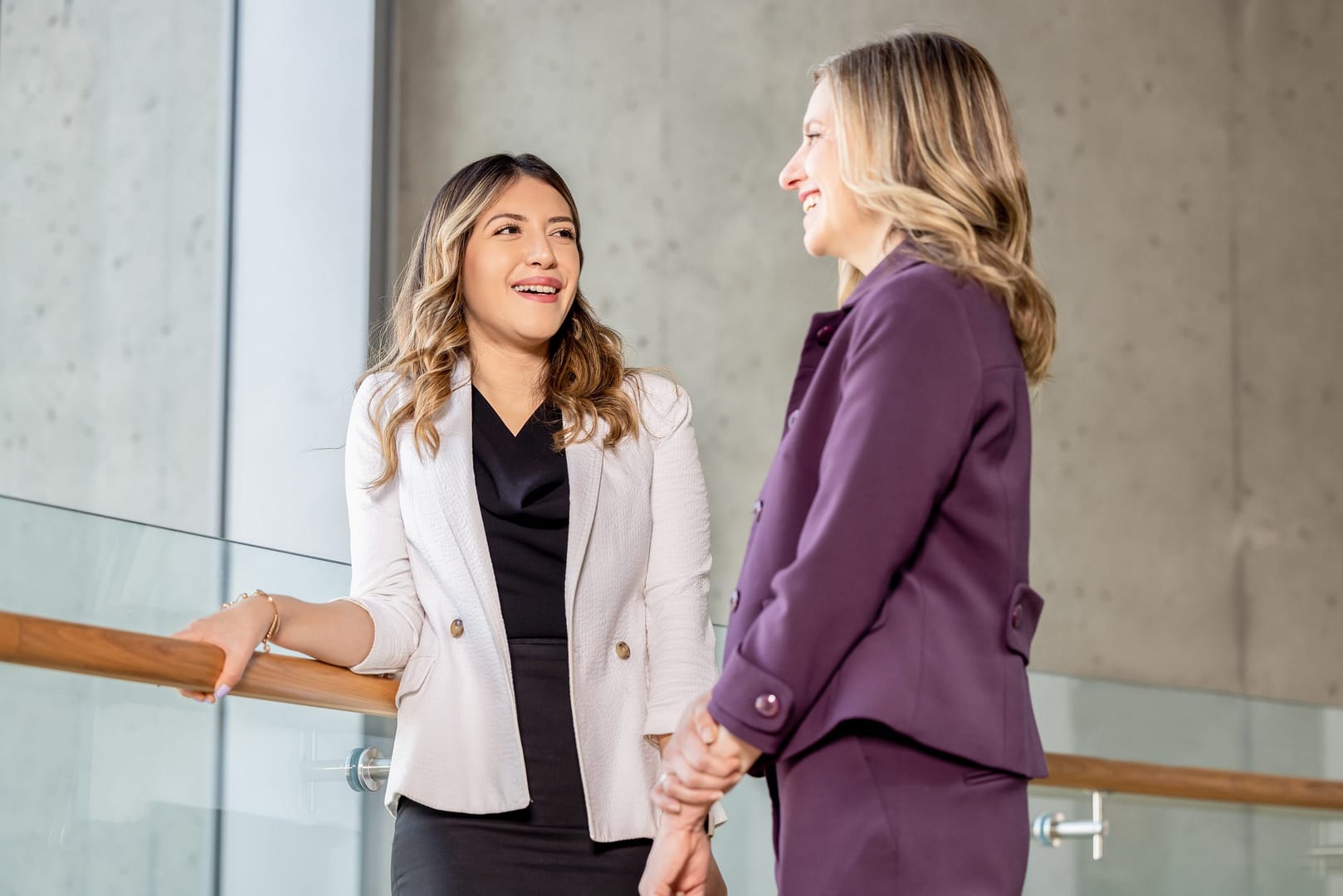 Two people in an office building standing and smiling Two people in an office building standing and smiling