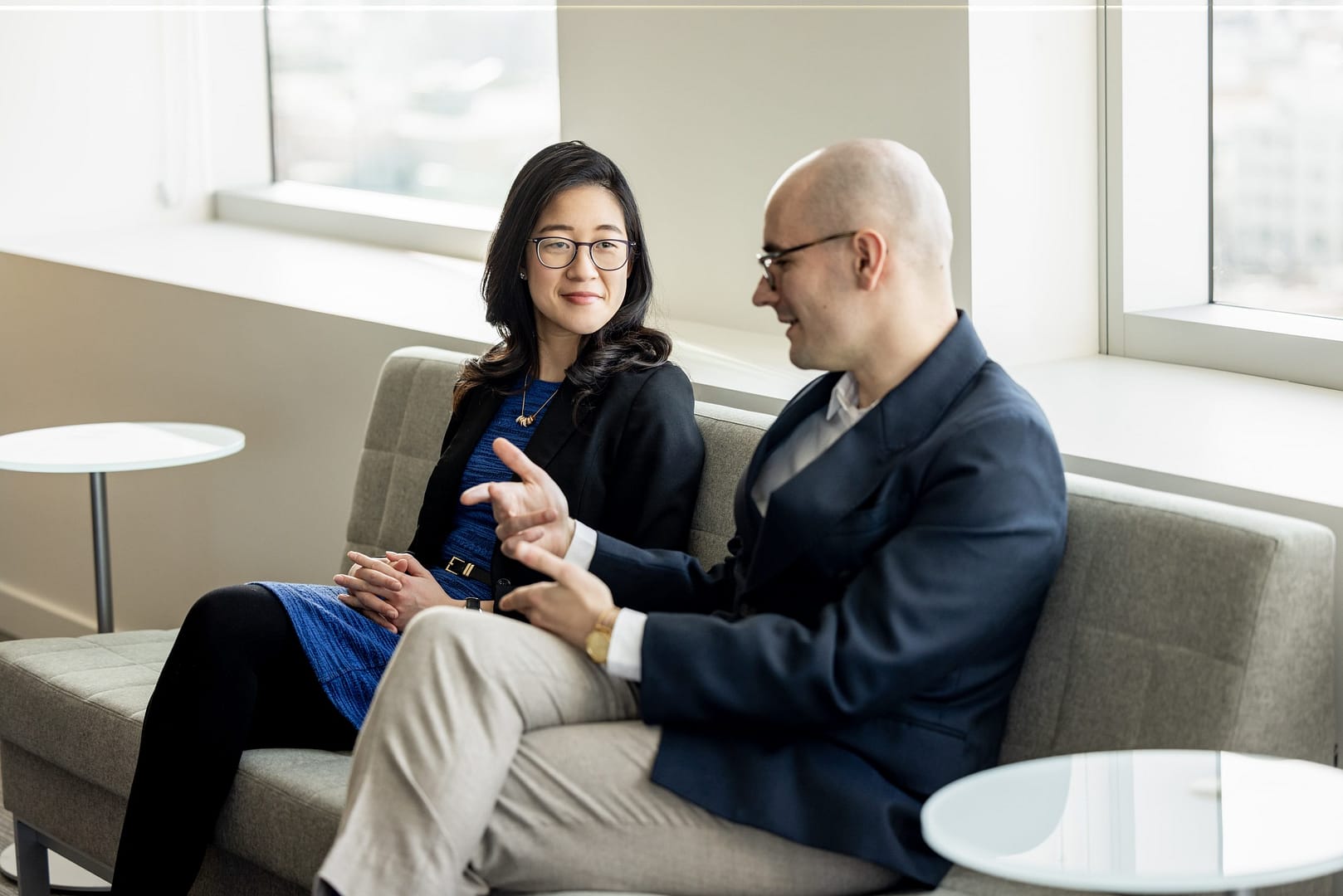 Two people on an office couch sitting down chatting Two people on an office couch sitting down chatting