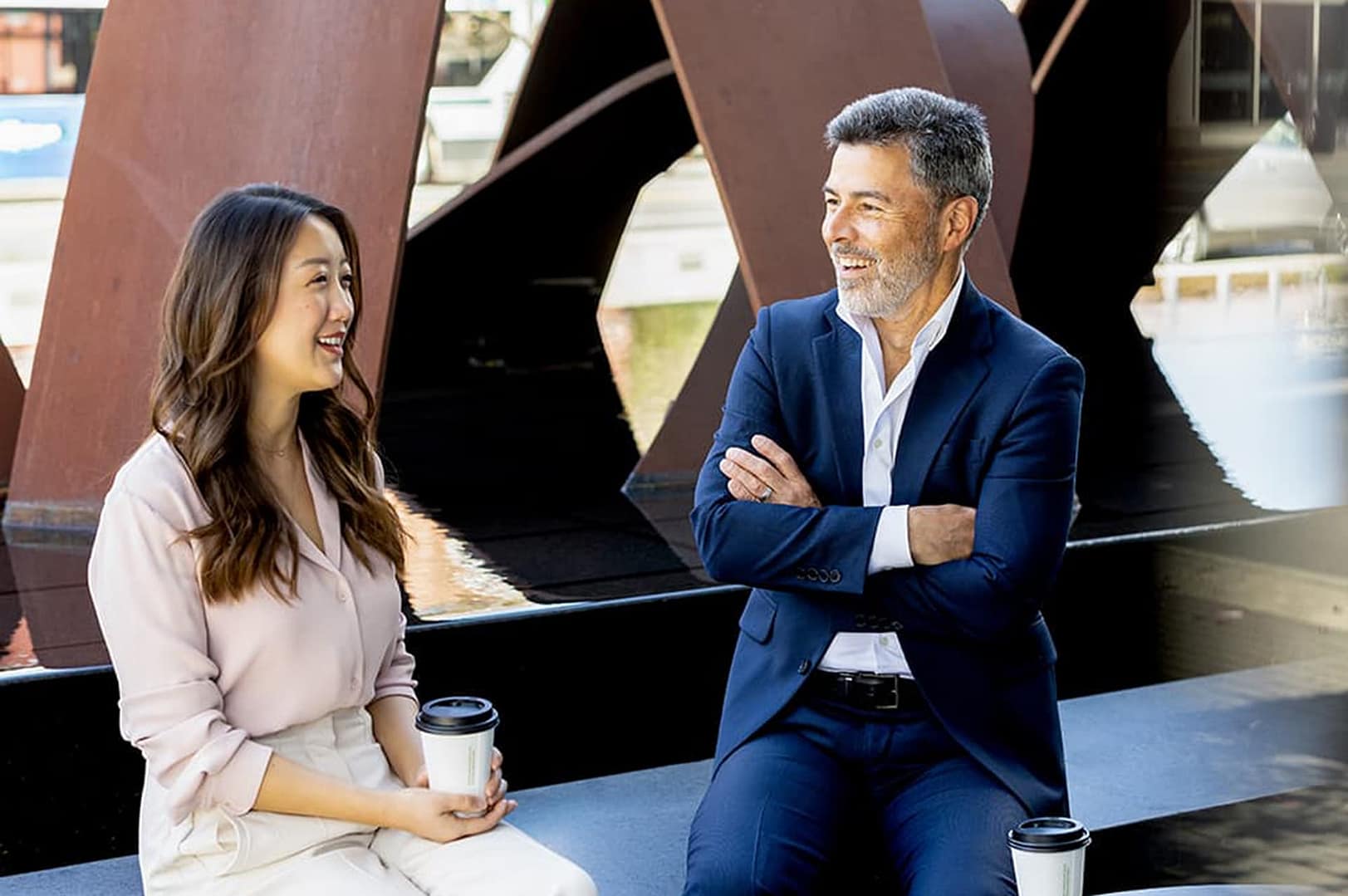 Two people drinking coffee at an outdoor fountain Two people drinking coffee at an outdoor fountain