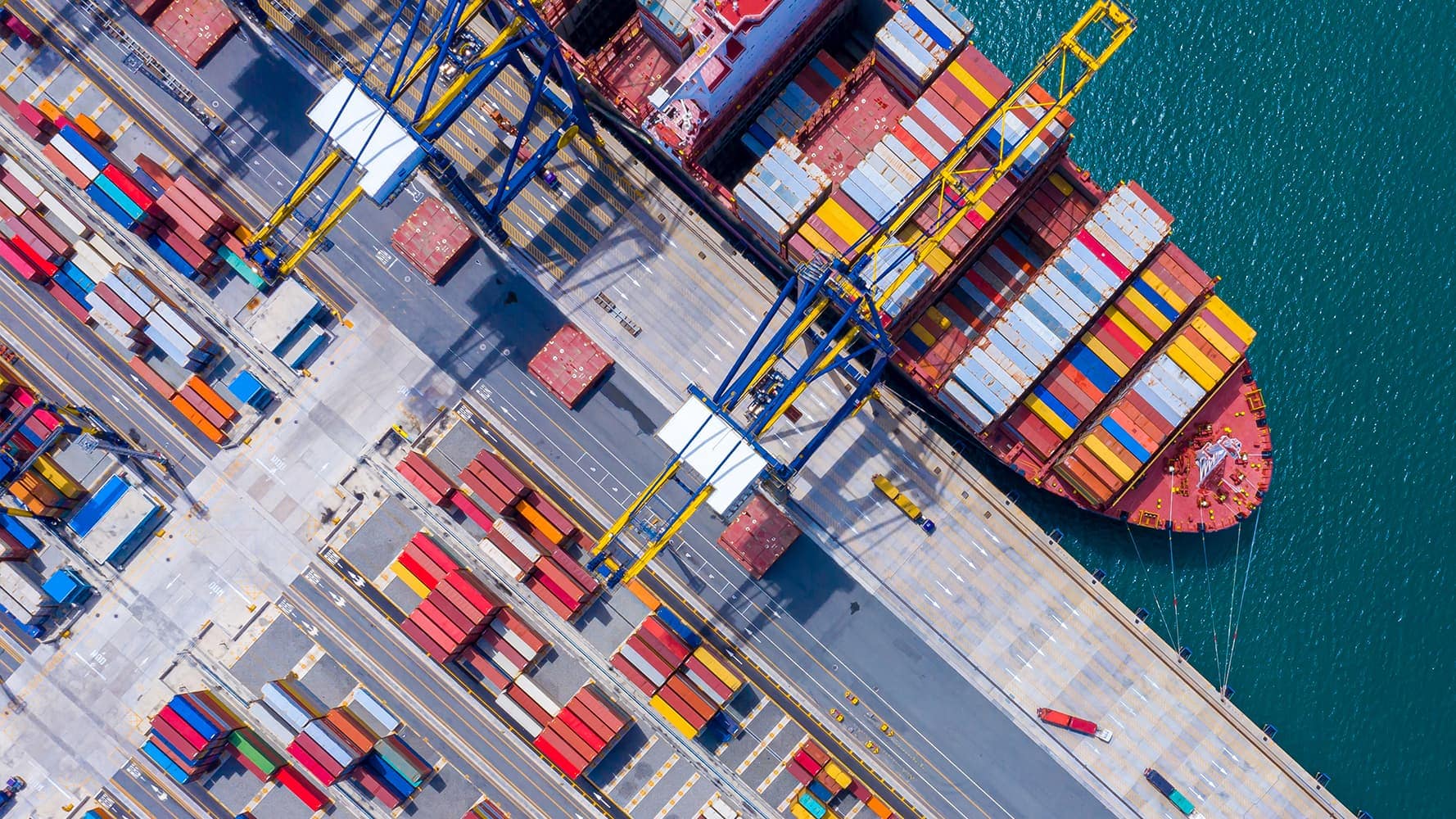 Overhead view of ship on water and shipping containers on land