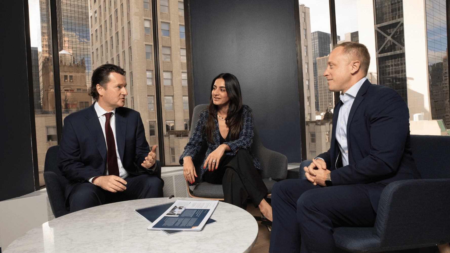 3 people sitting around a table talking 3 people sitting around a table talking