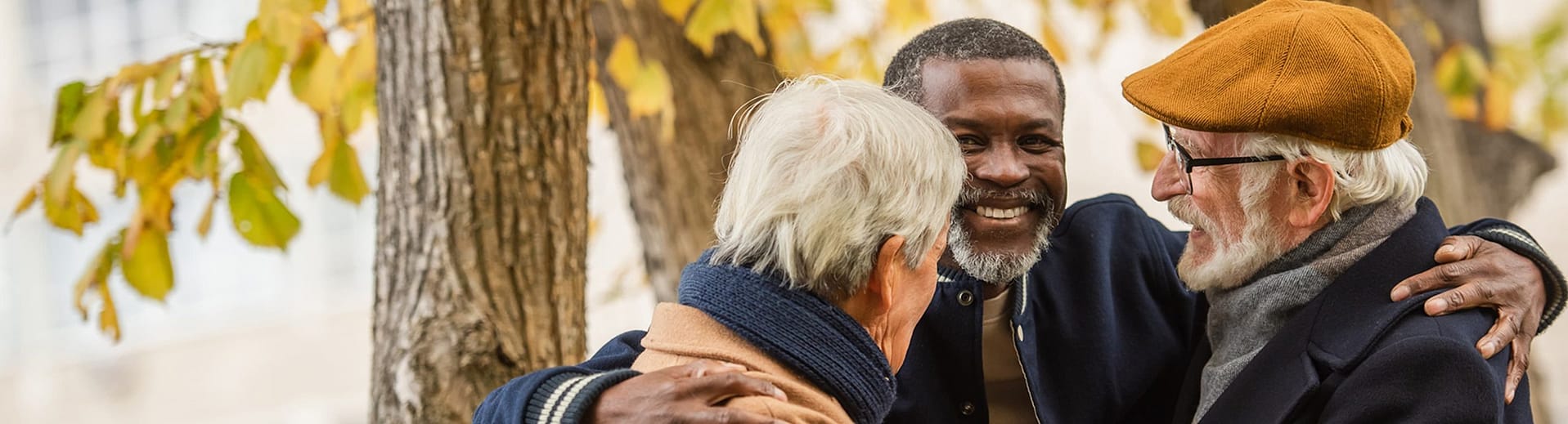 Three people embracing and smiling wearing autumn clothing Three people embracing and smiling wearing autumn clothing