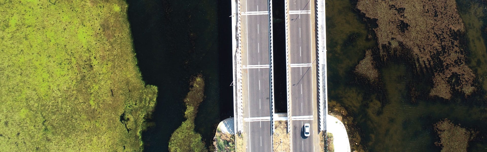 Overhead view of car driving over a bridge