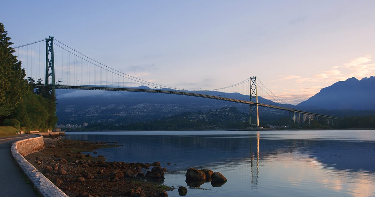 Bridge in Vancouver at sunset over ocean with mountains in the background