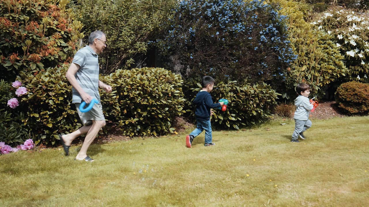 Grandfather chasing two young children in yard Grandfather chasing two young children in yard