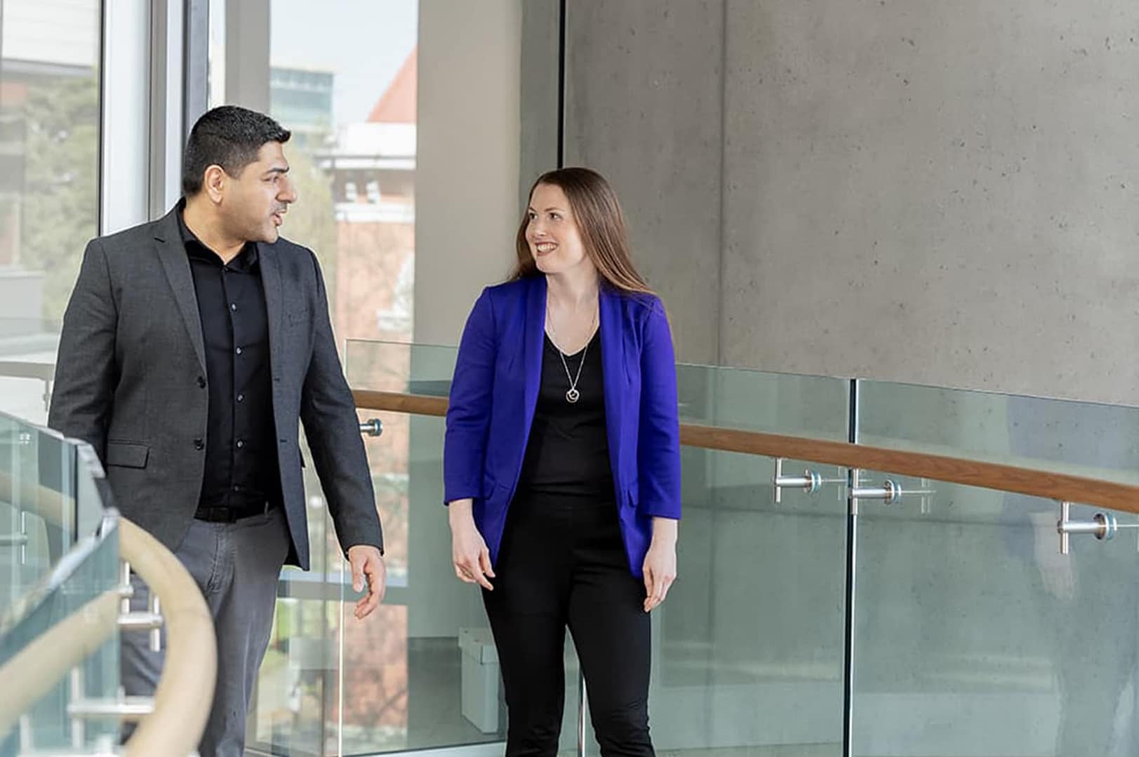 Two people walking and talking in an office building Two people walking and talking in an office building