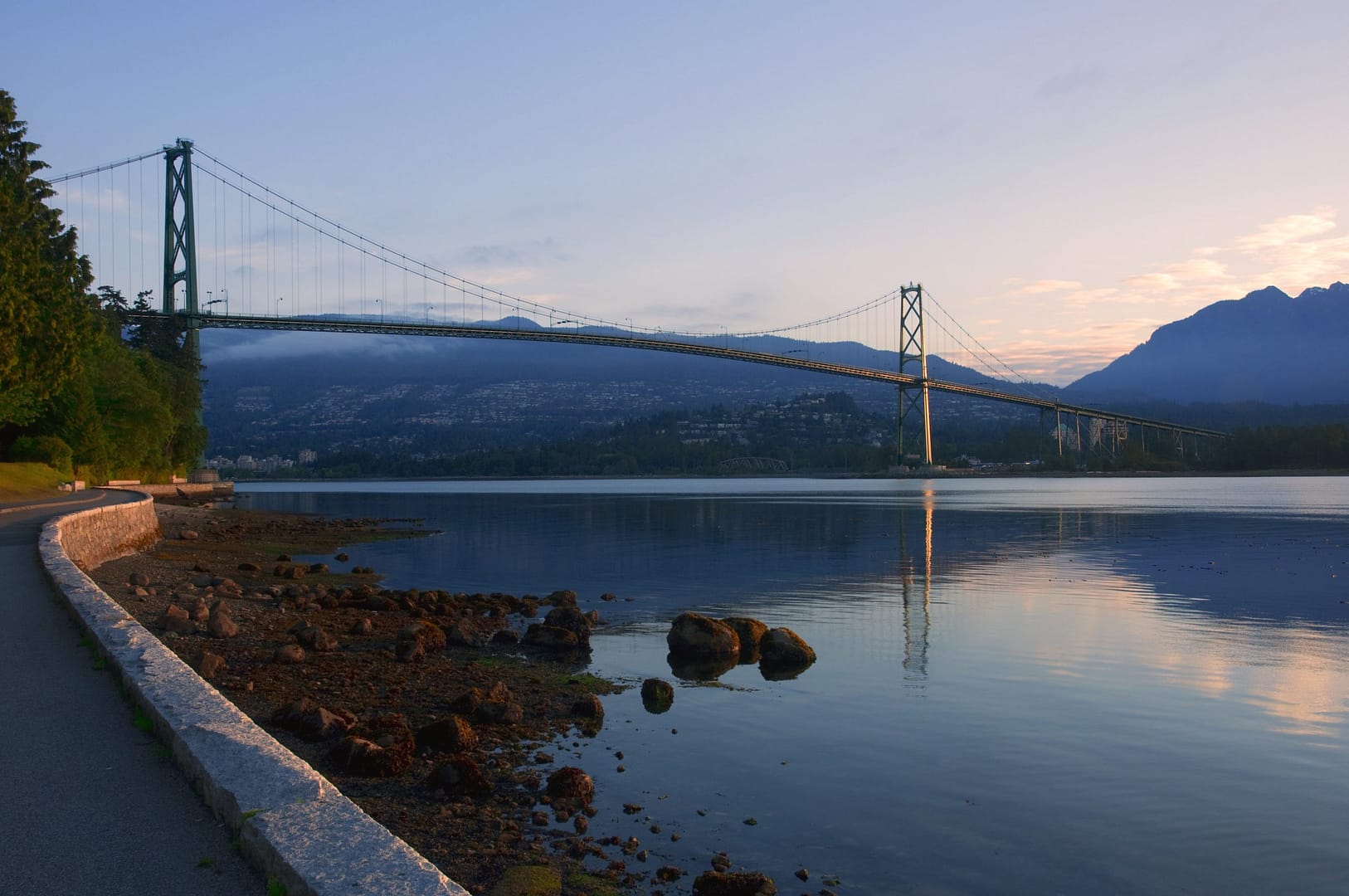 Bridge in Vancouver at sunset over ocean with mountains in the background Bridge in Vancouver at sunset over ocean with mountains in the background