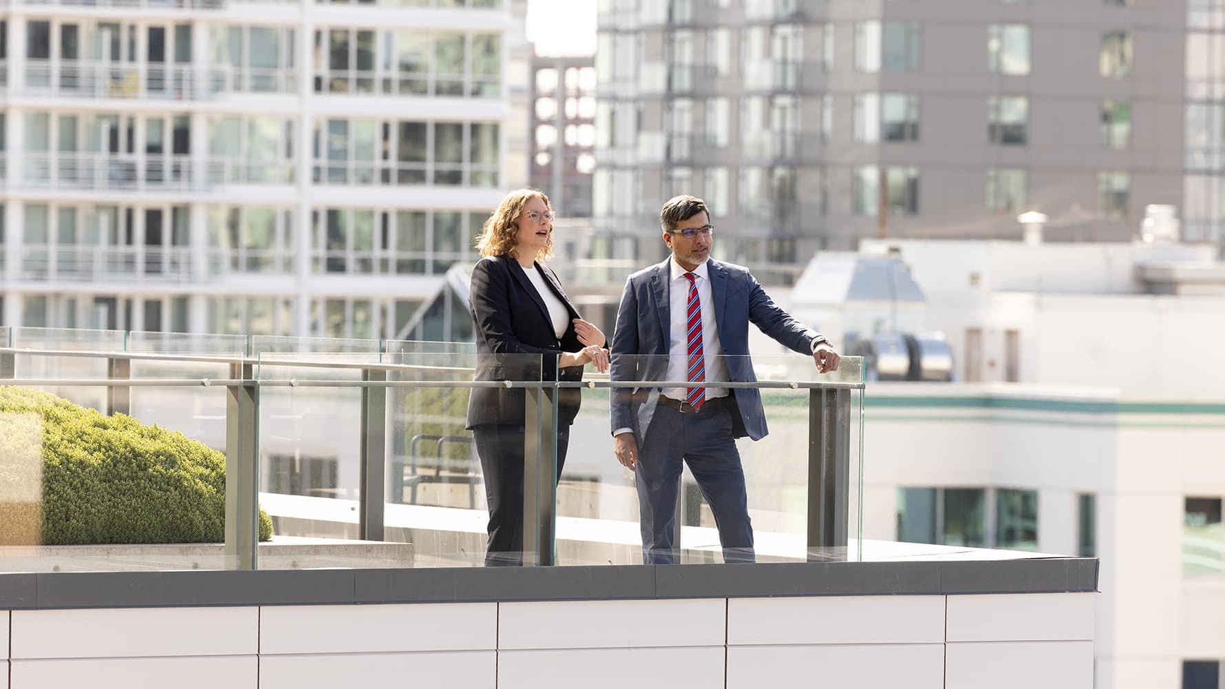 People standing on a balcony in a high-rise building in the city.