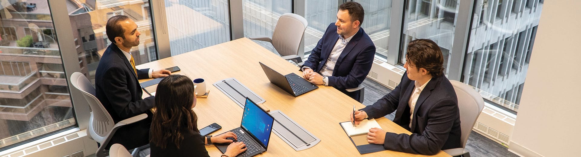 Four people working around a conference table Four people working around a conference table