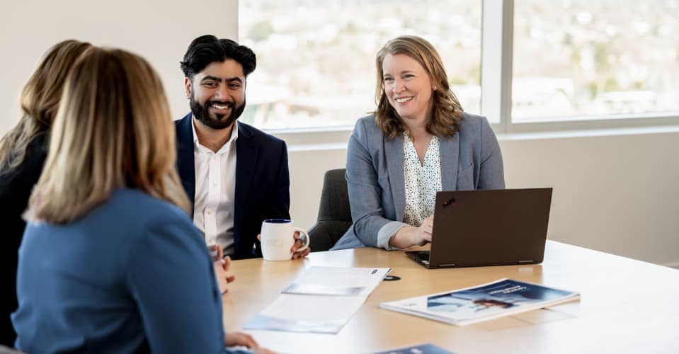 Four people in office building sitting at table smiling Four people in office building sitting at table smiling